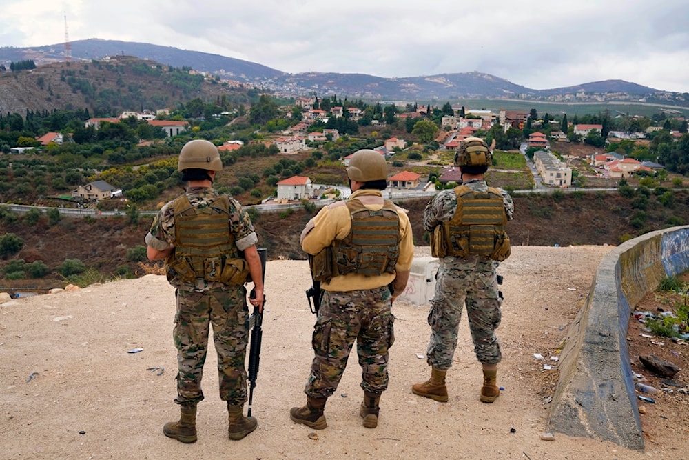 Lebanese army soldiers stand guard as they face the Israeli settlement of 'Metula', background, in the southern border village of Kfar Kila, Lebanon, October 15, 2023 (AP)