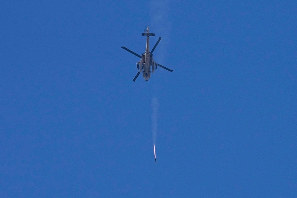 An Israeli Apache helicopter fires a missile in direction of the Gaza Strip, as seen from the occupied territories, Monday, Dec. 4, 2023. (AP Photo/Ohad Zwigenberg)