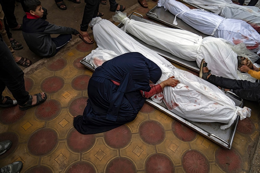 A woman mourns the covered bodies of her child and her husband killed in an Israeli army bombardment of the Gaza Strip, in the hospital in Khan Younis, Tuesday Dec. 5, 2023. (AP Photo/Fatima Shbair)