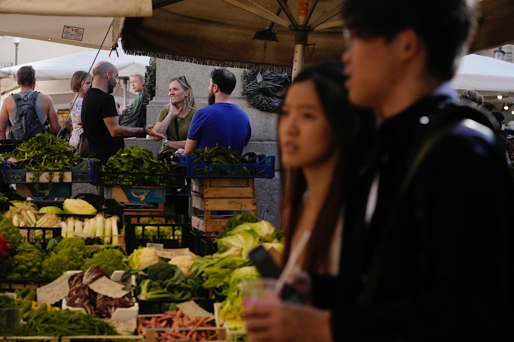 Tourists stroll past market stalls in Campo De' Fiori in Rome, Friday, Oct. 28, 2022. (AP)
