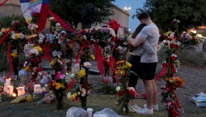 People hug as they visit a memorial to the victims of a mass shooting in Allen, Texas, U.S., May 7, 2023. (AFP