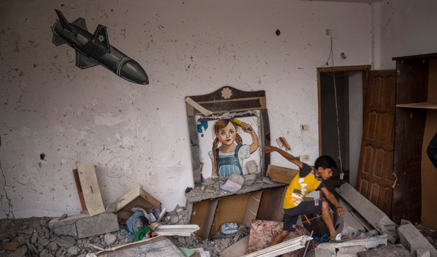 Palestinian children walk in the rubble behind them a mural painted in a house destroyed by the Israeli aggression, Deir al-Balah, central Gaza Strip, on June 8, 2023 (AP)