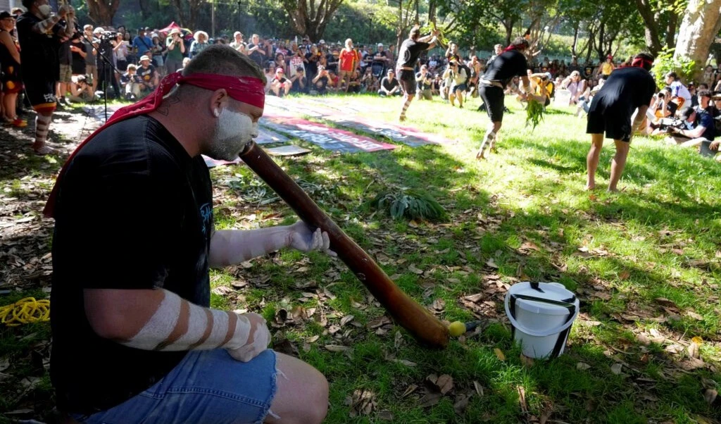 Aboriginal man Arron Nichols, left, plays a didgeridoo as other members of the Muggera Dancers perform at the start of an Invasion Day rally in Sydney, Thursday, Jan. 26, 2023 (AP Photo/Rick Rycroft)
