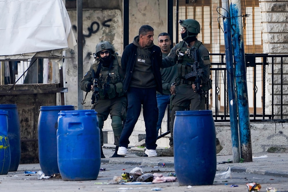 Israeli occupation forces arrest two Palestinian men during a military raid in the Askar refugee camp near the occupied West Bank city of Nablus, occupied Palestine, December 31, 2023 (AP)