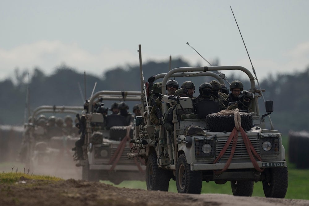 Israeli soldiers move near the Gaza wall as seen from southern occupied Palestine, January 3, 2024 (AP)