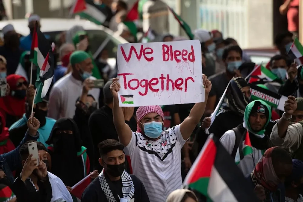 A demonstrator holds a placard as they march through the city Centre in Cape Town, on 12 May 2021 during a protest against Israeli attacks on Palestinians in Gaza (AFP via Getty Images)