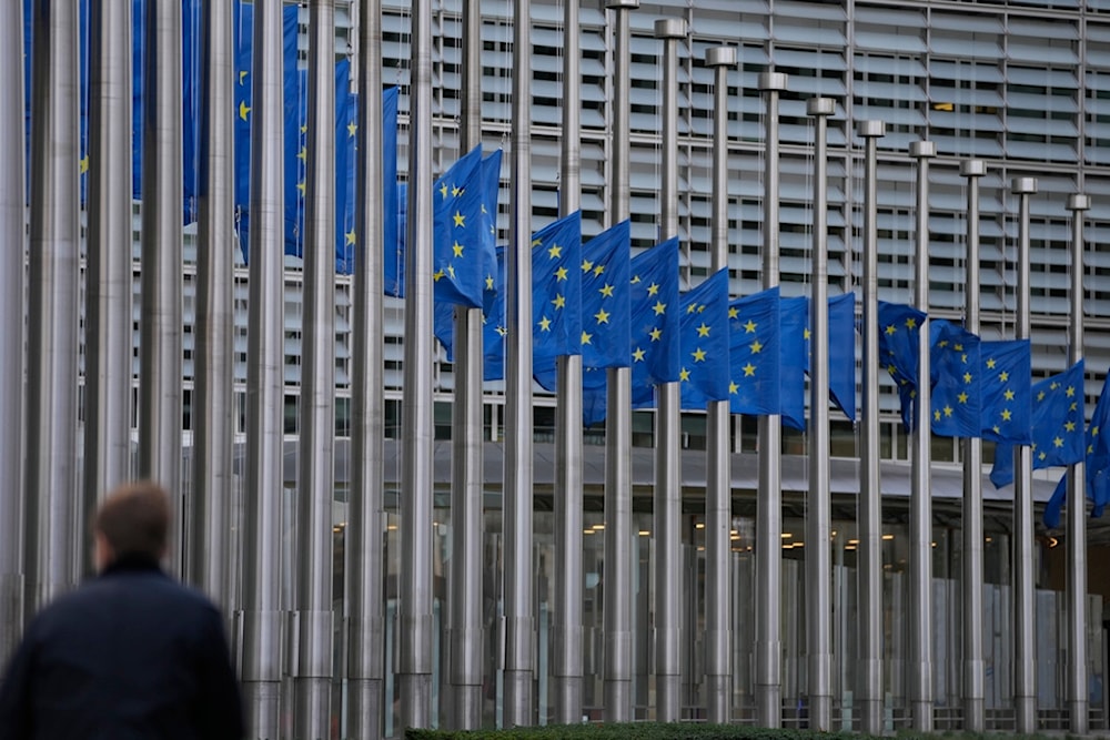 A man walks past European Union flags at half staff, in front of European Union headquarters in Brussels, Thursday, Dec. 28, 2023 (AP)