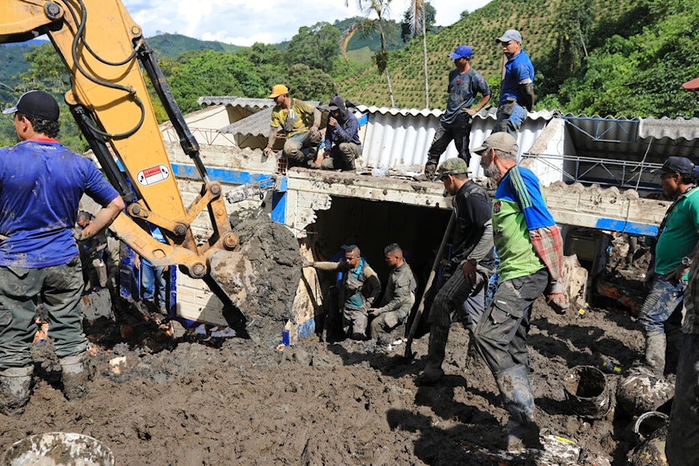 Residents and rescue workers look for survivors at a rural school buried by a landslide caused by heavy rains in Taparto, Colombia, Thursday, July 14, 2022 (AP)