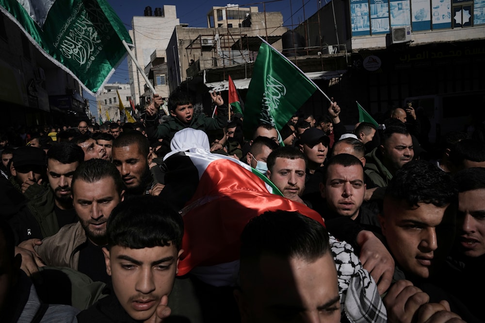 Mourners carry the body of Muhammad Sebaa, 22, a day after he and another woman were killed in confrontations against Israeli forces in the West Bank village of Dura, occupied West Bank, January 16, 2024 (AP)