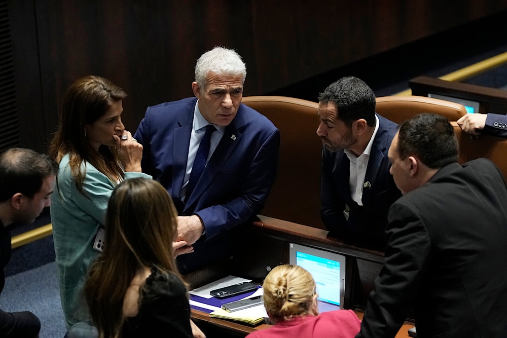 Israeli opposition leader Yair Lapid, center, confers with colleagues in the Knesset, occupied al-Quds, occupied Palestine, June 14, 2023 (AP)