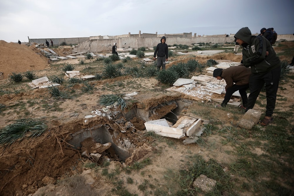 Palestinians inspect damaged graves following an Israeli tank raid over a cemetery in Khan Younis refugee camp, southern Gaza Strip, Wednesday, Jan. 17, 2024 (AP)