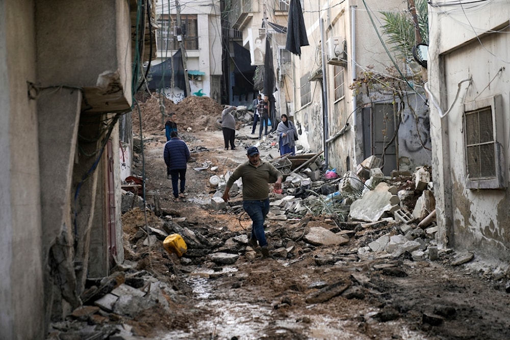 Palestinians walk through the aftermath of the Israeli military raid on Nur Shams refugee camp in the West Bank, Wednesday, Dec. 27, 2023 (AP Photo/Majdi Mohammed)