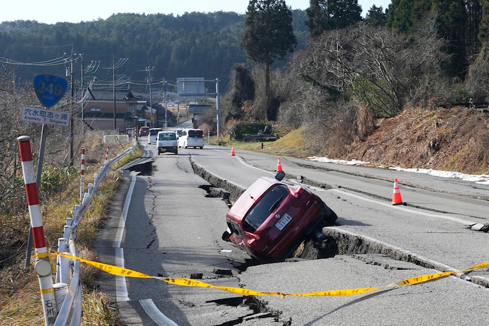 A car is trapped at a partially collapsed road caused by a powerful earthquake near Anamizu Town, Ishikawa Prefecture Tuesday, Jan. 2, 2024. (AP)