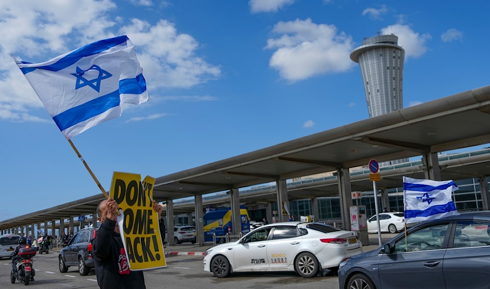 A man holds a sign reading 'don't come back' and an Israeli flag in Ben Gurion airport near 'Tel Aviv', 'Israel', Wednesday, March 15, 2023. (AP)