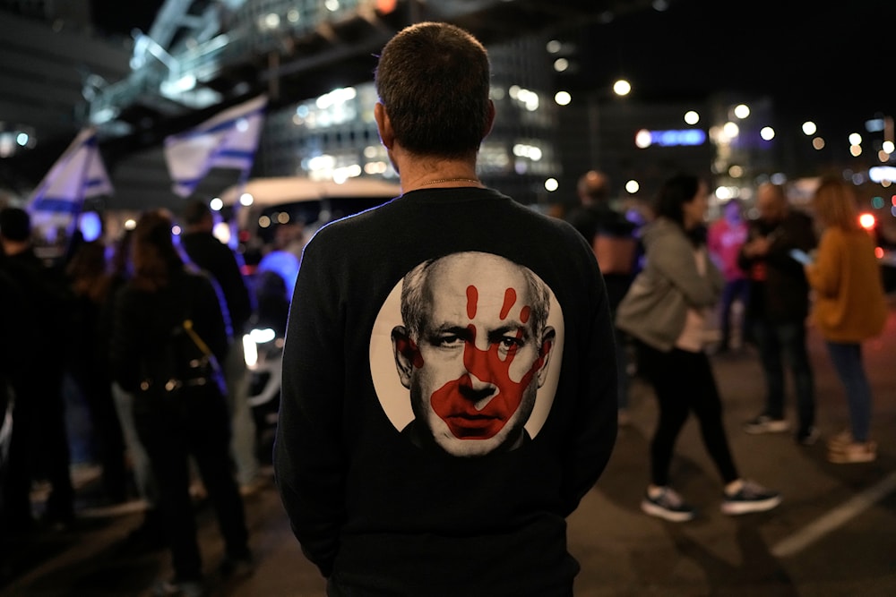 A protester wears a shirt depicting Israeli Prime Minister Benjamin Netanyahu during a demonstration to demand the release of the captives taken during Operation al-Aqsa Flood, in 'Tel Aviv', occupied Palestine, January 20, 2024 (AP)