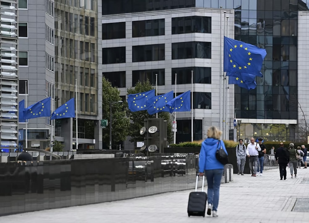 Pedestrians walk past as European Union flags flap, in front of European Union headquarters in Brussels, Thursday, Dec. 28, 2023. (AFP)