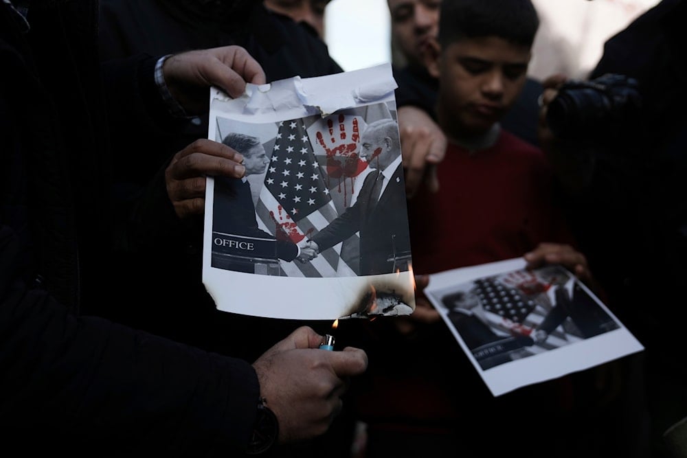 Palestinians burn a photo of Israeli Prime Minister Benjamin Netanyahu and US Secretary of State Antony Blinken during a protest in Ramallah, West Bank, occupied Palestine, January 10, 2024 (AP)