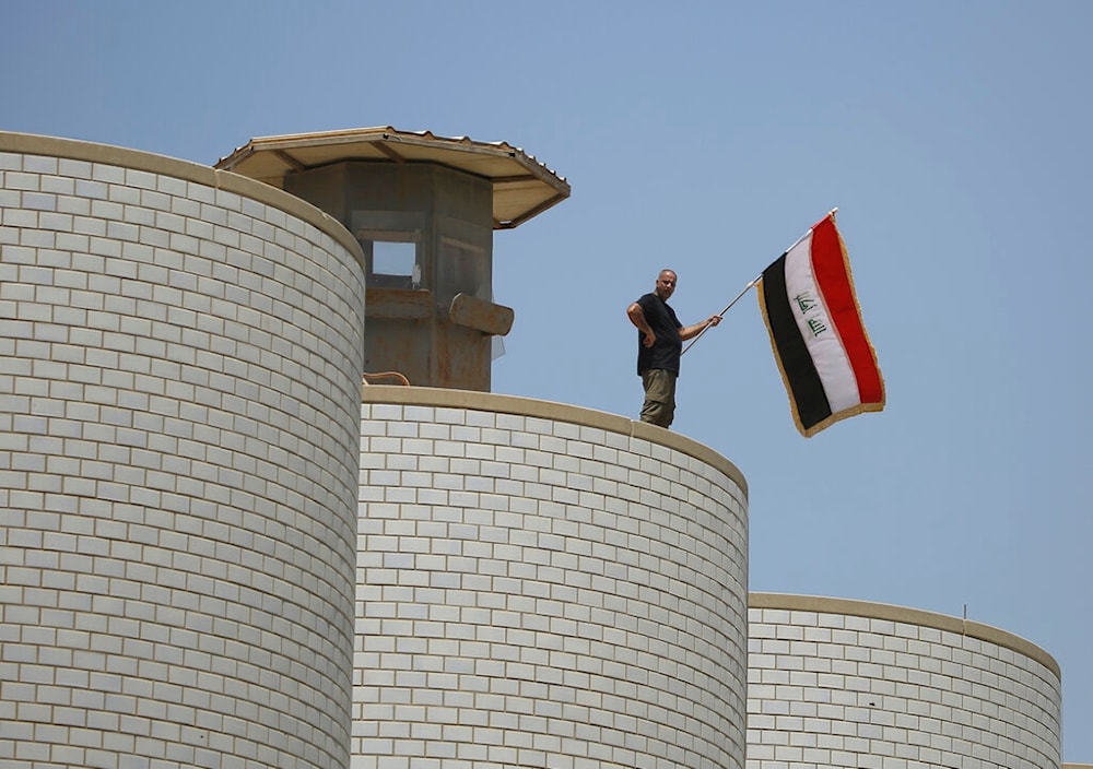 A man waves the Iraqi flag above the Iraqi parliament building in Baghdad, Iraq, Saturday, July 30, 2022.(AP)