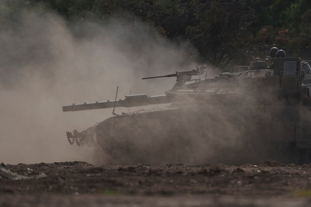 Israeli soldiers move on the top of a tank near the Gaza strip, as seen from southern occupied Palestine, January 23, 2024 (AP)