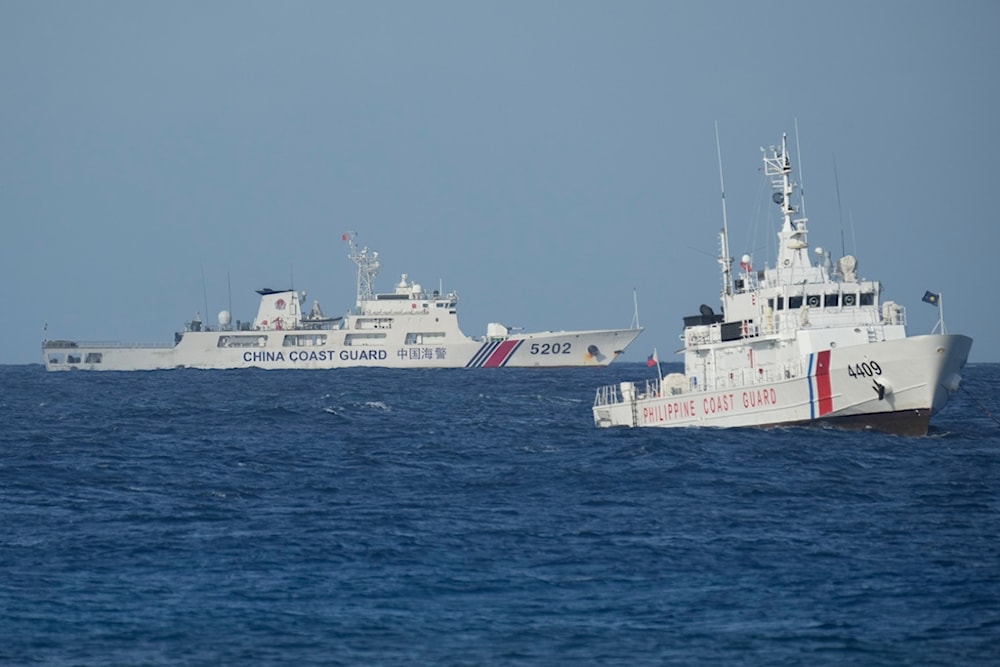 A Chinese coast guard vessel, left, passes by a Philippine coast guard ship near the Philippine-occupied Thitu island, locally called Pag-asa island, on Dec. 1, 2023 at the disputed South China Sea.