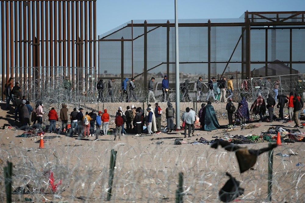 Migrants line up after being detained by U.S. immigration authorities at the U.S. border wall, seen from Ciudad Juarez, Mexico, Wednesday, Dec. 27, 2023 (AP Photo/Christian Chavez)