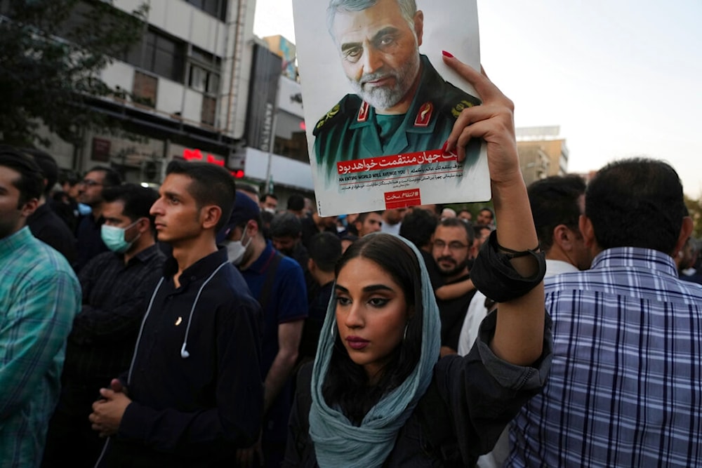 Iranian woman holds up portrait of Late IRGC commander Qassem Soleimani in Tehran, Iran, Sunday, Sept. 25, 2022 (AP)