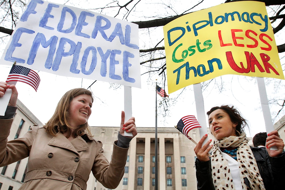 Susanne Brands, 22, left, and Mina Seljogi, 21, both interns at the American Foreign Service Association, attend a rally of U.S. diplomats and federal workers against the prospect of a government shutdown, Friday, April 8, 2011, in Washington(AP)