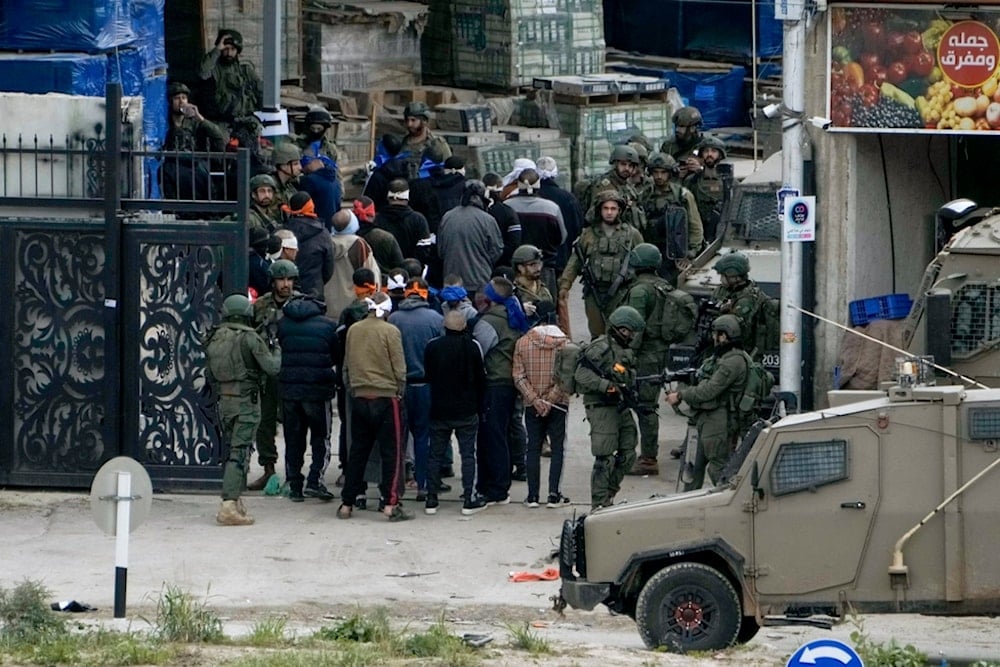 Israeli security forces arrest Palestinian men during a military raid in Nur Shams refugee camp in Tulkarem, West Bank, occupied Palestine, on Wednesday, Jan. 3, 2024. (AP)