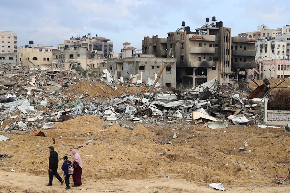 Palestinians walk past the building destroyed in the Israeli Bombardment of the Gaza Strip in Gaza City on Wednesday, Jan. 3, 2024 (AP)