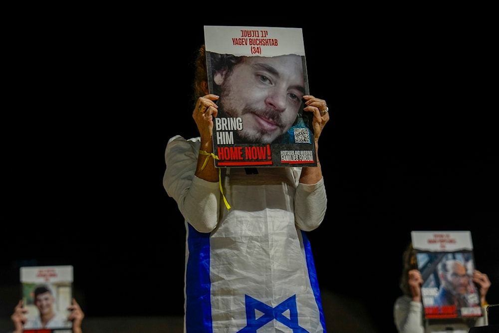 Families and supporters of Israeli captives hold their photos and shout slogans during a rally calling for their release, in 