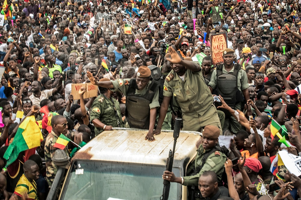 An unidentified representative of the junta waves from a military vehicle as Malians supporting the overthrow of President Ibrahim Boubacar Keita gather to celebrate in the capital Bamako, Mali, August 21, 2020 (AP)