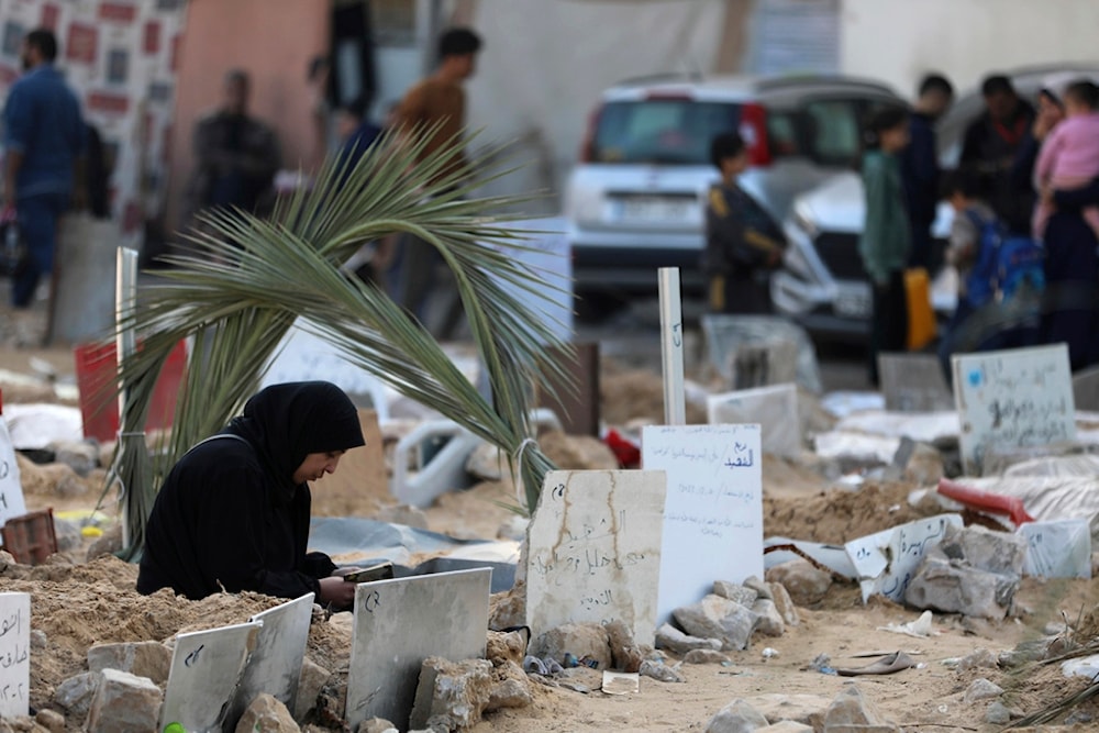 Palestinians visit the graves of people killed in the Israeli bombardment of the Gaza Strip and buried inside the Shifa Hospital grounds in Gaza City, Sunday, Dec. 31, 2023. (AP)