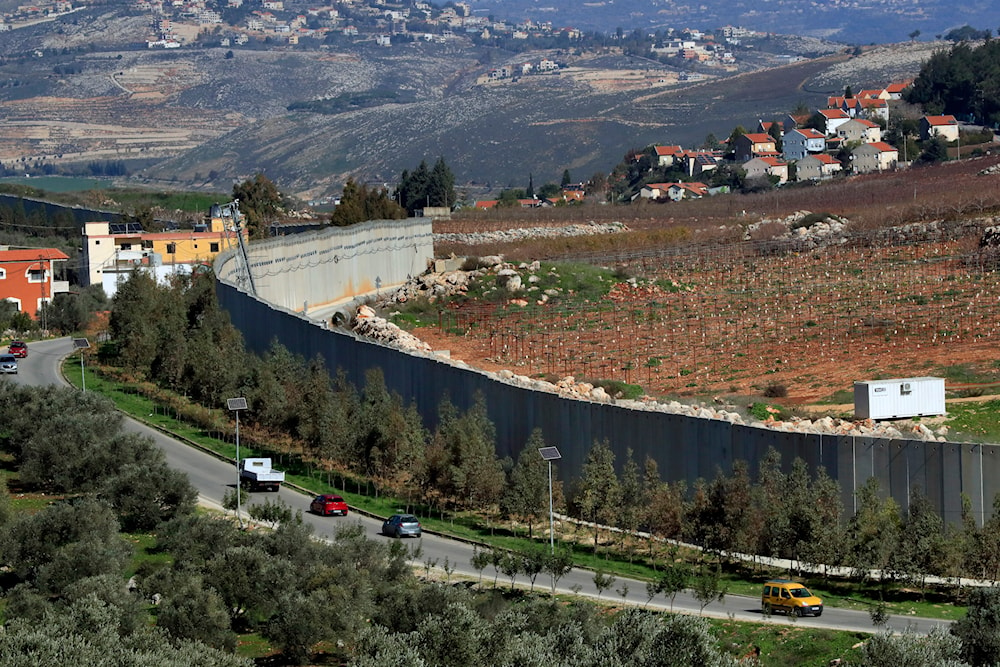 Cars drive next to the wall that separates Lebanon from Israel in the southeastern Lebanese village of Kfar Kila, Saturday, Jan. 21, 2023. (AP)