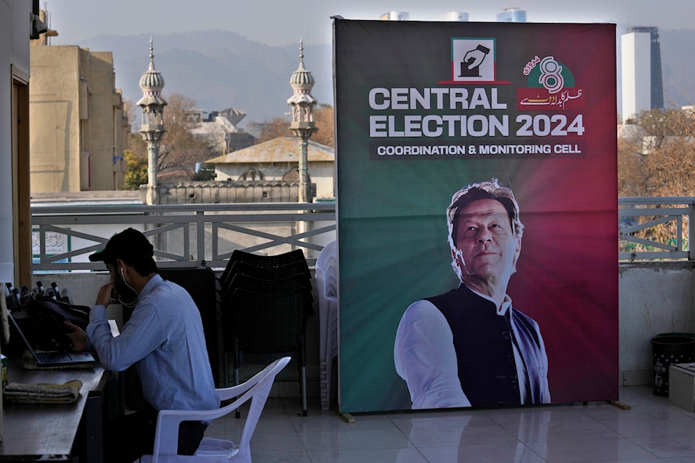 A supporter works on his desk next to a poster of Pakistan's Former Prime Minister Imran Khan displayed at his party office, in Islamabad, Pakistan, Friday, Feb. 9, 2024(AP)