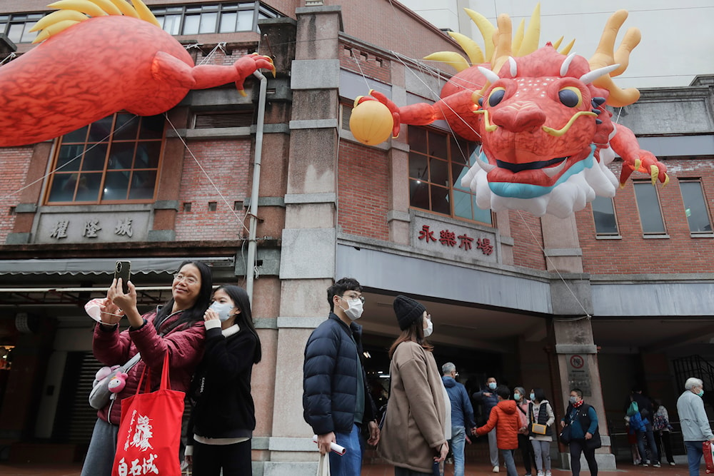 People walk under dragon balloons decorated on a building for the upcoming Lunar New Year celebrations at the Dihua street market in Taipei, Taiwan, Thursday, Feb. 8, 2024. (AP)