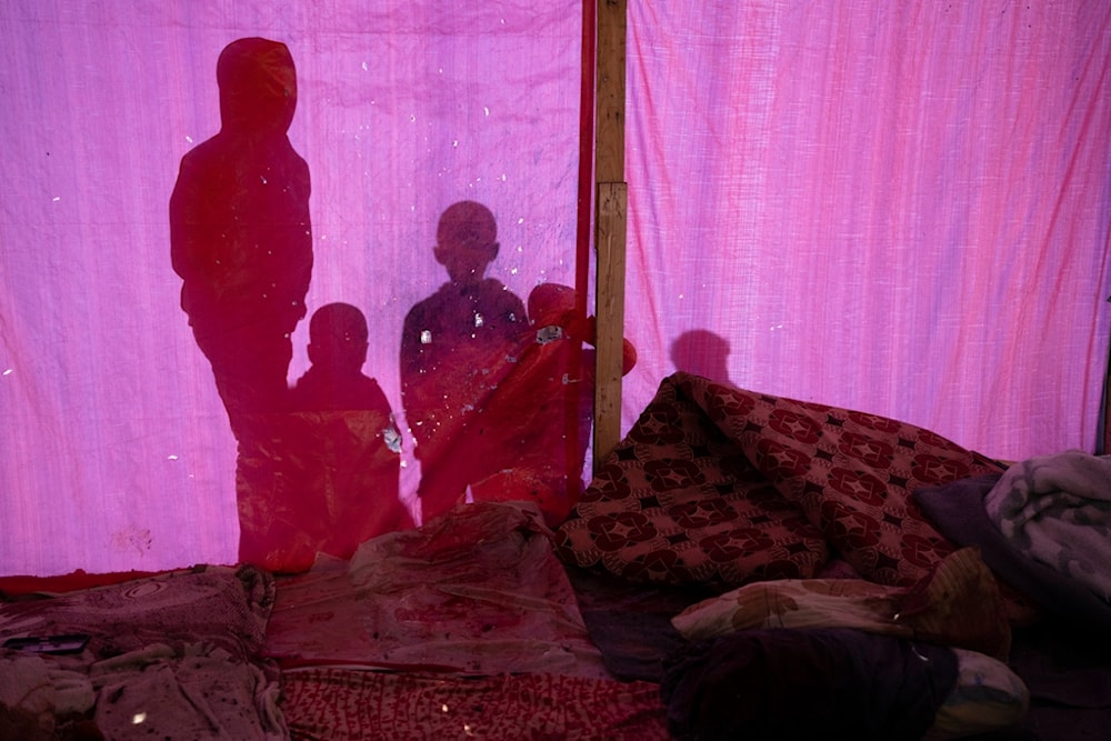 Palestinians are silhouetted on a damaged tent following the Israeli occupation's airstrike in Rafah, southern Gaza Strip, Palestine, Feb. 12, 2024. (AP)