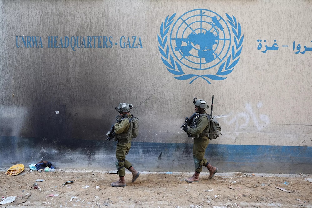Two Israeli invading soldiers pass by UN premises in Gaza. (AFP)