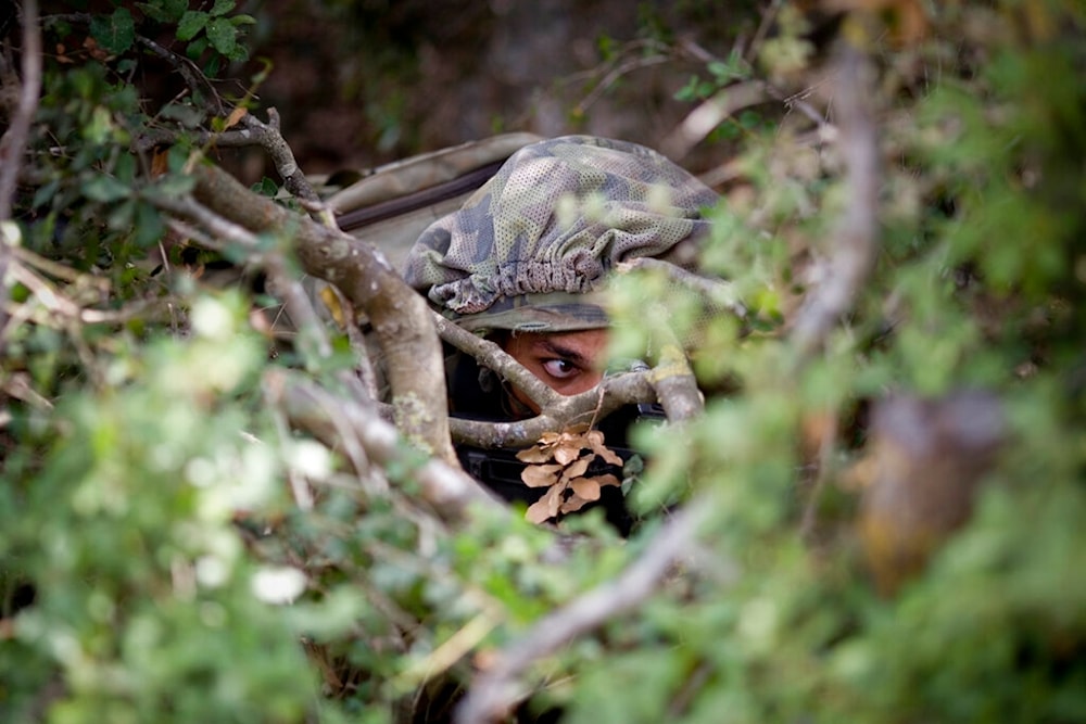In this photo taken Wednesday, July 21, 2010, an Israeli occupation soldier from the Golani Brigade takes position during training in a forest simulating military posts in south Lebanon. (AP)
