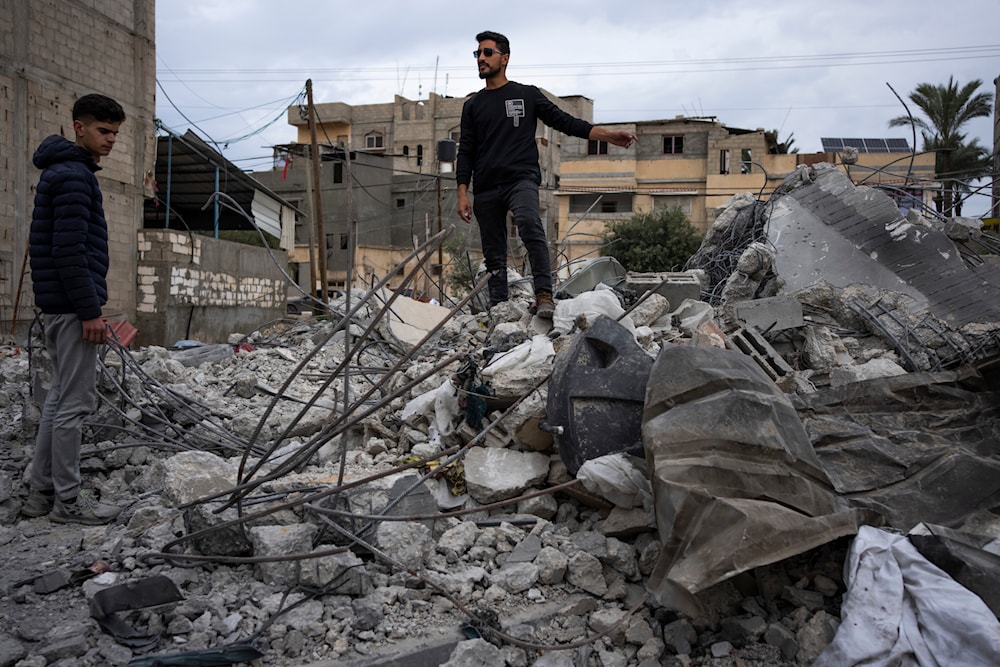 Ibrahim Hasouna, center, the sole survivor among his family, stands amidst the debris of his bombed home in Rafah, southern Gaza Strip, Tuesday, Feb. 13, 2024(AP)