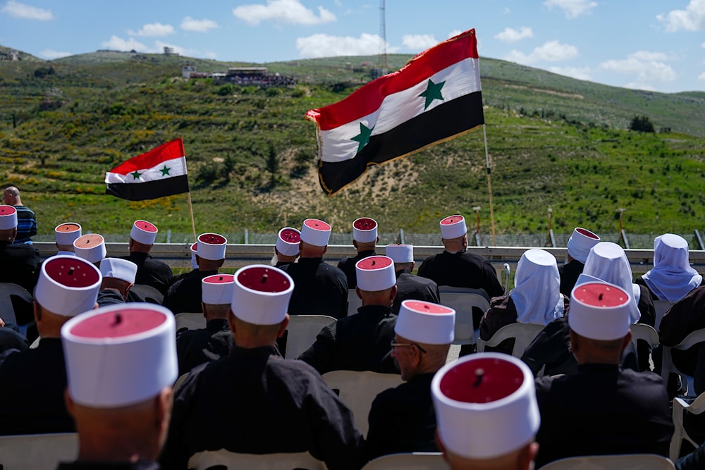 Druze men sit with Syrian flags during a rally marking Syria's Independence Day, in the Druze village of Majdal Shams in the Israeli-controlled Golan Heights, on the border with Syria, Monday, April 17, 2023. (AP)