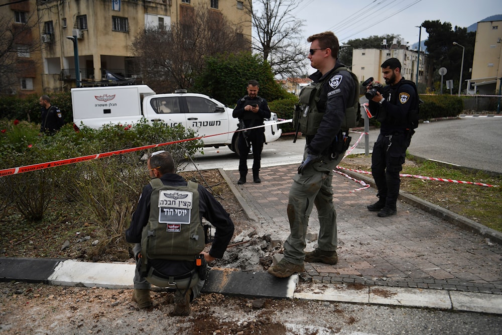 Israeli occupation forces examine the site hit by a rocket fired from Lebanon, in 'Kiryat Shmona', northern occupied Palestine, February 13, 2024 (AP)