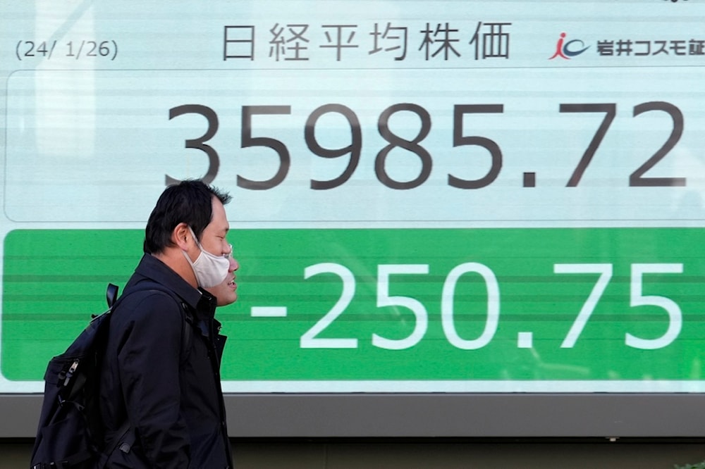 People walk in front of an electronic stock board showing Japan's Nikkei 225 index at a securities firm Friday, Jan. 26, 2024, in Tokyo (AP)