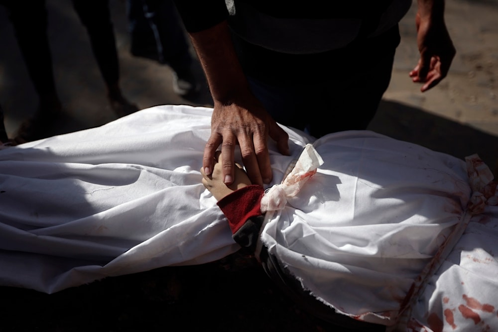 A Palestinian man mourns over the body of a child killed in the Israeli bombardment of the Gaza Strip at Nasser Hospital in Khan Younis, Monday, Jan. 22, 2024. (AP)