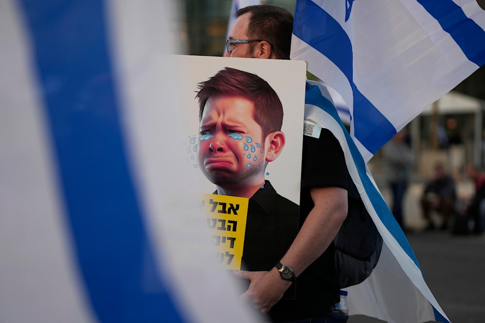 An Israeli protesting plans by Prime Minister Benjamin Netanyahu's far-right government carries a caricature of son Yair Netanyahu on April 1, 2023. (AP)