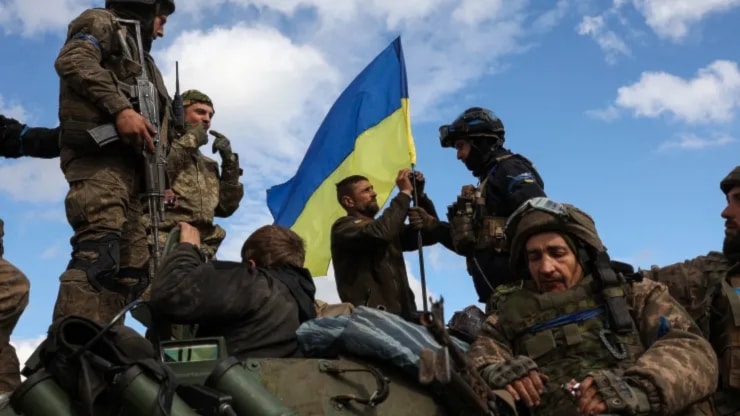 Ukrainian soldiers adjust their national flag atop a personnel armored carrier on a road near Lyman, in the Donetsk region, on Oct. 4, 2022. (AFP via Getty Images)