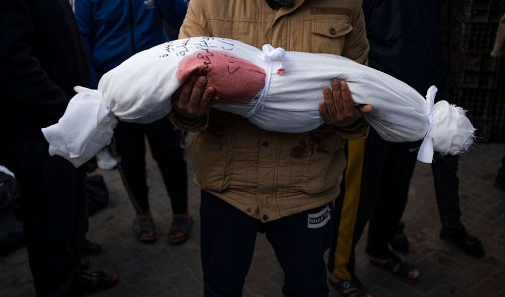 A man holds the body of his daughter who was killed in the Israeli occupation's bombardment of the Gaza Strip, at a hospital morgue in Rafah, Wednesday, Feb. 21, 2024. (AP)
