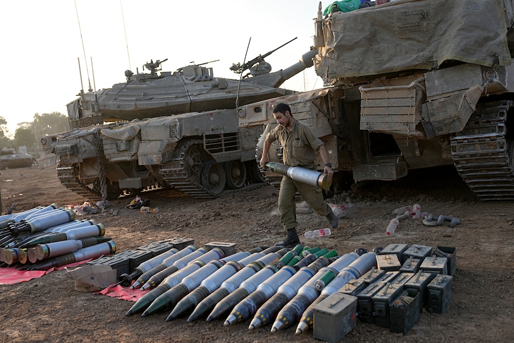 IOF troops load shells onto a tank at a staging area in southern occupied Palestine near the border with Gaza on Sunday, Dec. 31, 2023(AP)
