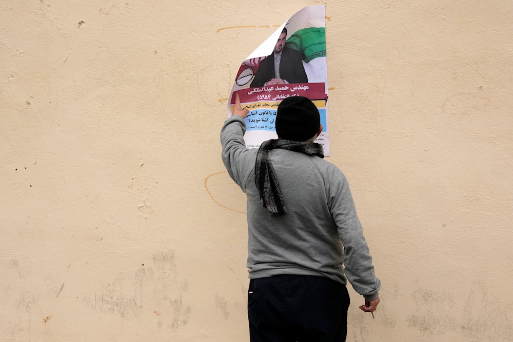 A man looks at an electoral poster of Hamid Abdolmaleki, a candidate for the March 1, parliamentary election, in Tehran, Iran, Thursday, Feb. 22, 2024. (AP)