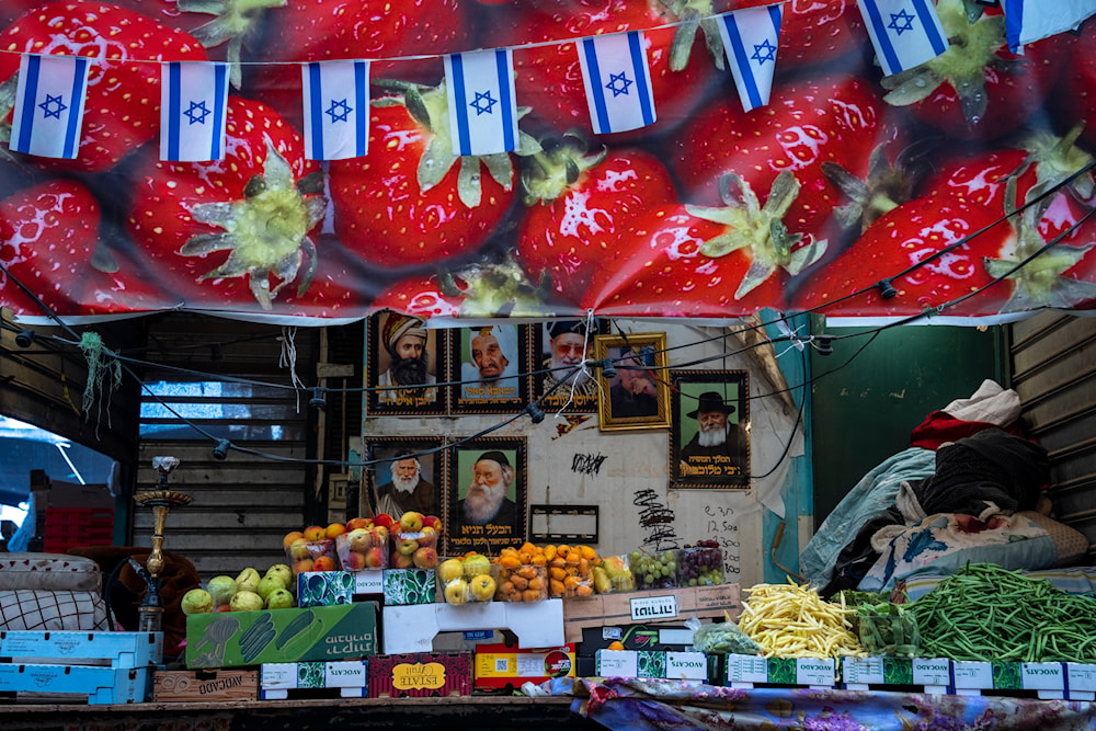 Israeli occupation flags above a fruit store at a market, in occupied Palestine Monday, April 17, 2023.(AP)