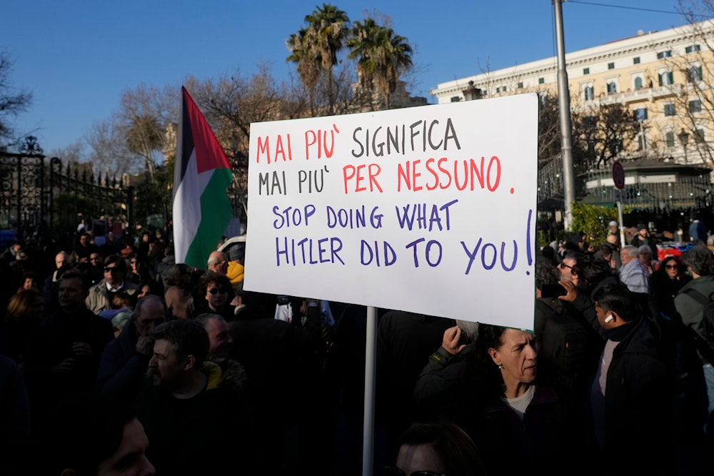 A demonstrator holds a placard reading in Italian: 'Never Again Means Never Again Anyone', during a demonstration in support of Palestinians, in Rome, Saturday, Jan. 27, 2024. (AP)